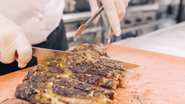 Preparation of grilled t-bone steak on a plate in the restaurant kitchen. - Φωτογραφία, εικόνα
