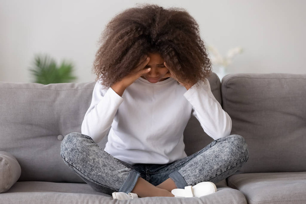 Depressed upset african american teen girl feeling hurt sitting alone - Foto, afbeelding