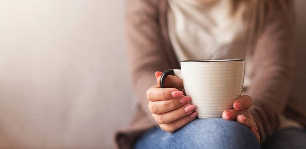 Xícara de café quente em mãos de menina milenar
 - Foto, Imagem