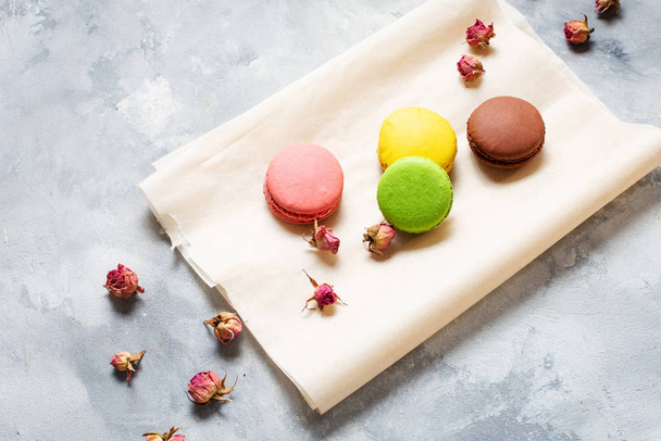 Different types of macaroons and pink flowers on concrete background. - Photo, Image