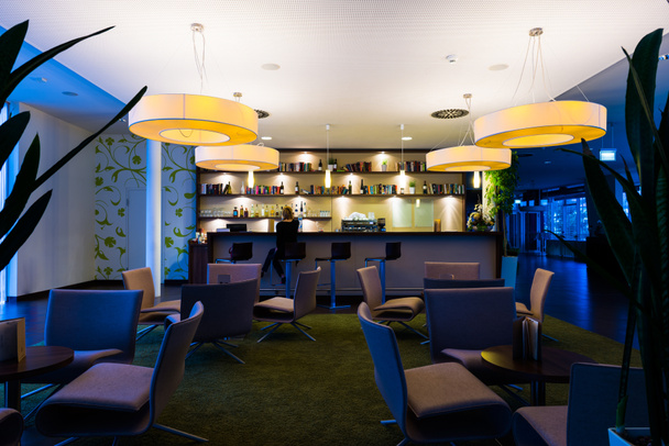 Chica solitaria se sienta sola en el moderno bar del hotel iluminado
 - Foto, imagen