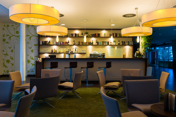 Bel hôtel bar-salon avec étagères à bouteilles et sièges, tables, lumières
 - Photo, image
