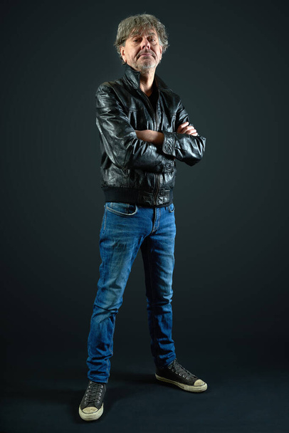 Portrait of a man with leather jacket and denim pant on gradient background - Foto, imagen