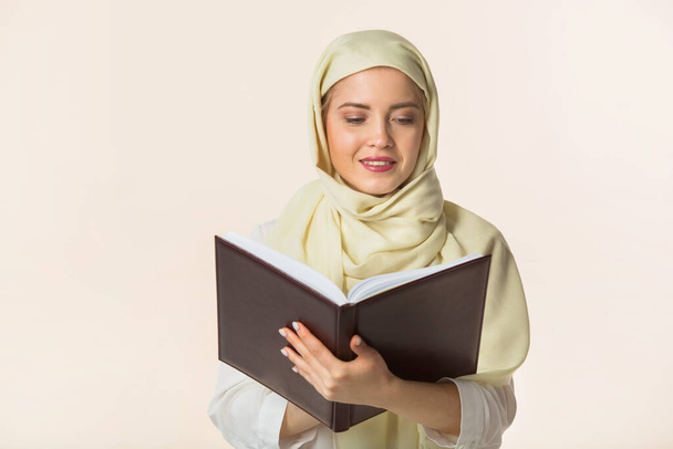 bella giovane donna in uno scialle musulmano con un libro in mano
 - Foto, immagini