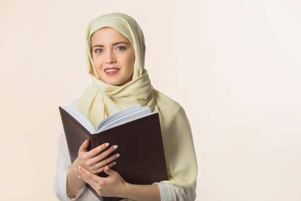 beautiful young woman in a muslim shawl with a book in her hands - Foto, Imagem