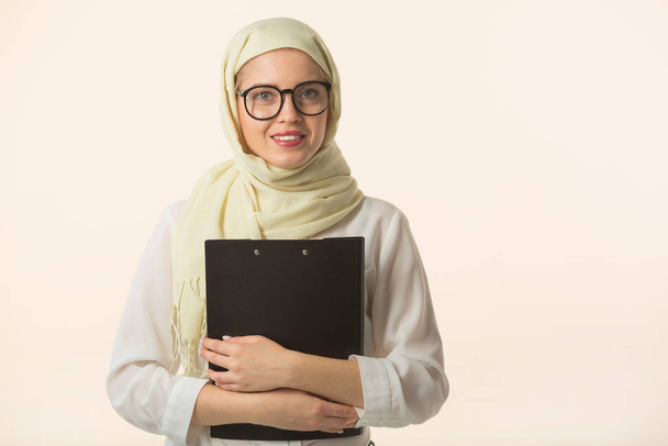 mooie jonge vrouw in een moslim sjaal met een map in haar handen - Foto, afbeelding