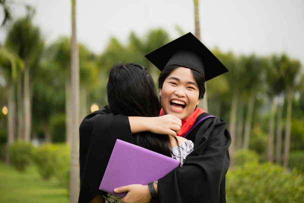 Cérémonie de remise des diplômes. Jeune diplômée s'embrassant avec son amie félicite l'étudiante à l'université
. - Photo, image