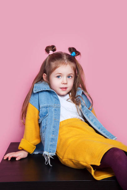 Cute little girl model in denim sitting in studio Fashion concept - Фото, зображення