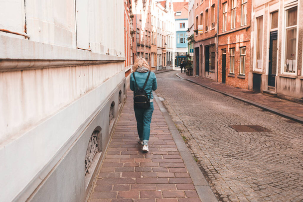 A woman walks along an empty street in Bruges, Belgium. - Zdjęcie, obraz