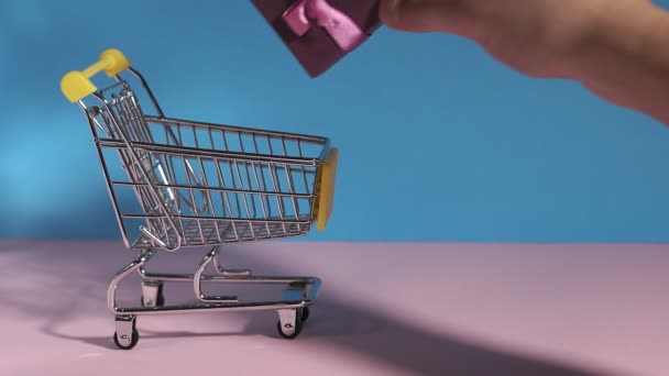 Mini alışveriş arabası el hediye koyar. e-ticaret, çevrimiçi alışveriş ve iş pazarlama kavramını kullanarak. - Video, Çekim