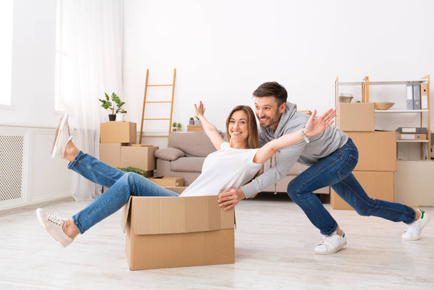 Smiling young couple having fun and riding in boxes - Foto, Imagem