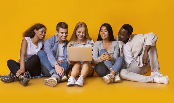 International group of teenagers looking at laptop screen - 写真・画像