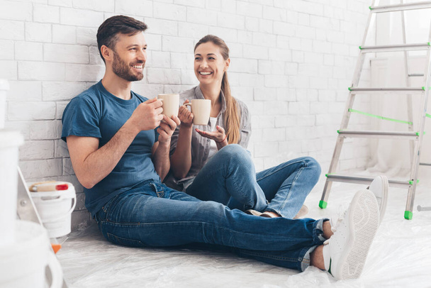 Young couple drinking hot tea after making repairs - Foto, Bild