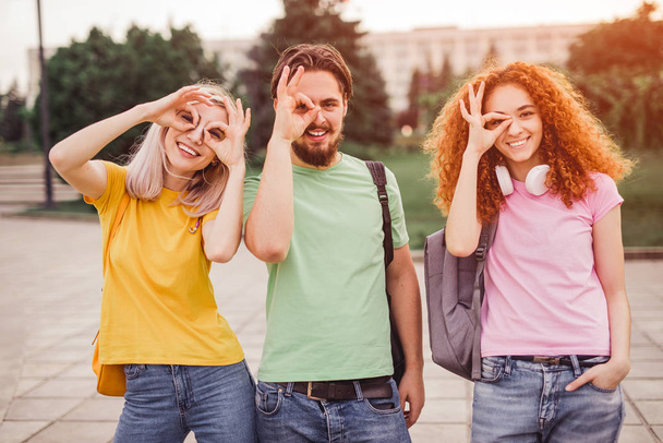 Cheerful students gesturing OK near faces - Foto, afbeelding