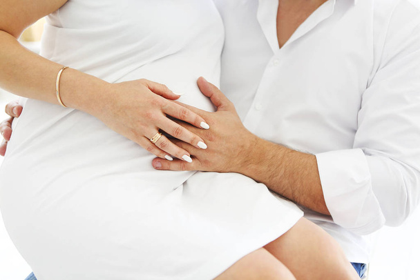 Kale volwassen man aanraken buik van zwangere vrouw terwijl rusten op comfortabel bed in gezellige kamer thuis - Foto, afbeelding