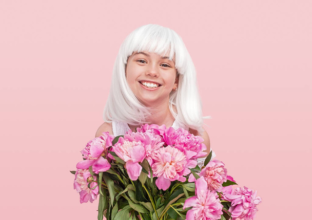 Happy teenager in wig carrying flowers - Фото, изображение