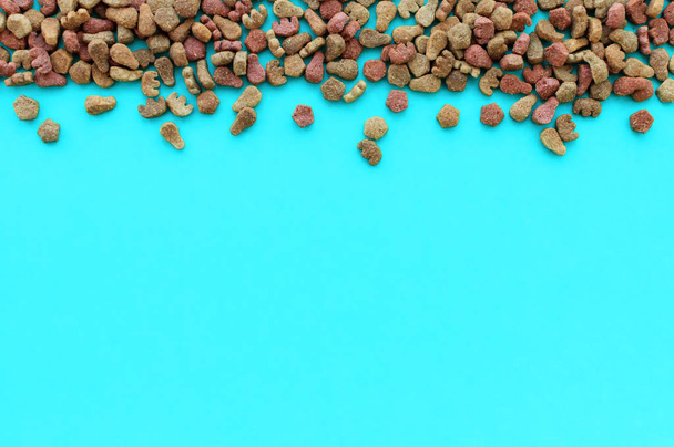 Dry cat food on a blue background with a place for writing. The view from the top - Fotoğraf, Görsel