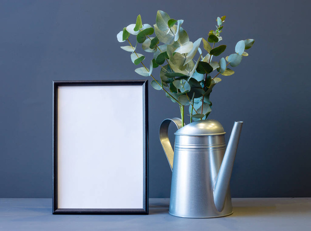 marco de fotos y regadera de metal con flores de brunia sobre un fondo gris con espacio de copia
 - Foto, imagen