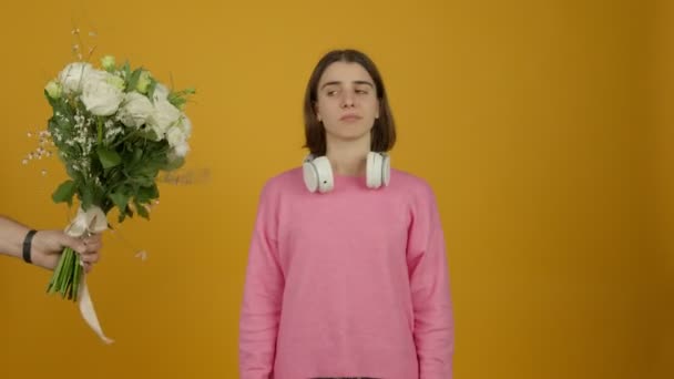 Excited girl in headphones looking at flowers and showing yes gesture with smile - Footage, Video