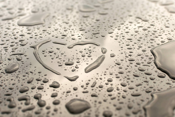 Heart made of water drops on a glass mirror. The symbol of love and passion is drawn by hand. Wet gray surface with condensation and raindrops. Background with copy space for a romantic greeting card. - Foto, Imagem