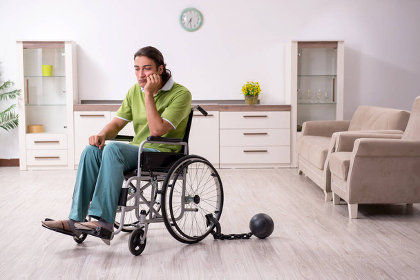 Jeune homme invalide en fauteuil roulant souffrant à la maison
 - Photo, image