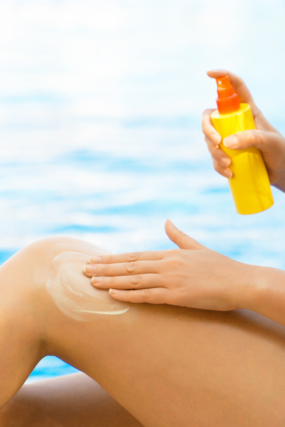Mujer aplicando crema protector solar en sus piernas. - Foto, imagen