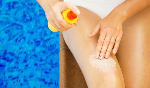 Woman applying sunblock cream on her legs. - Foto, imagen