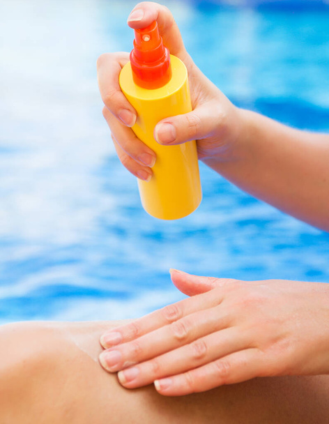 Mujer aplicando crema protector solar en sus piernas. - Foto, Imagen