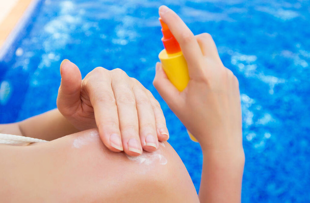 Woman applying sunblock cream on her shoulder. - Photo, Image
