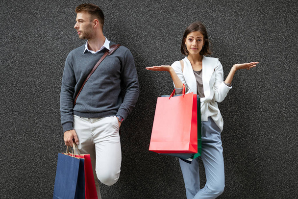 Beautiful young shopaholic woman with shopping addition. Unhappy husband man. Black friday concept. - Fotoğraf, Görsel