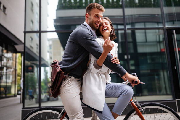 Beautiful happy young couple in love on bicycle in the city having fun - Фото, изображение