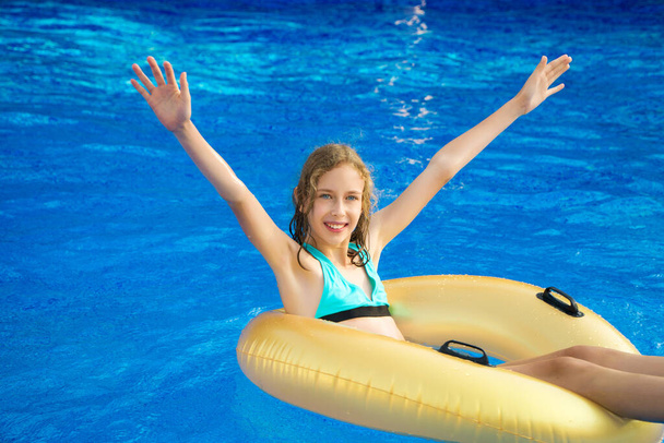 Little girl with inflatable rubber ring having fun in swimming pool. Place for text. - Фото, изображение