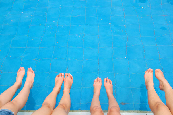 Női lábak és lábak a kék vizes klórral töltött uszodában  - Fotó, kép