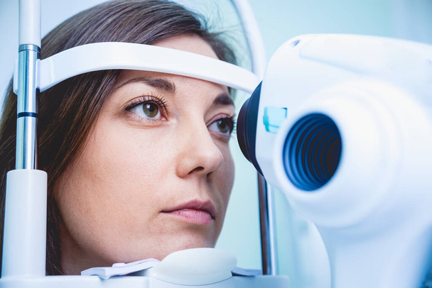 Médico examinando os olhos das mulheres com uma máquina de medição
. - Foto, Imagem
