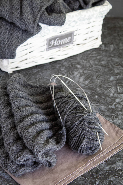 Una palla di lana e maglia grigia su fondo grigio
 - Foto, immagini