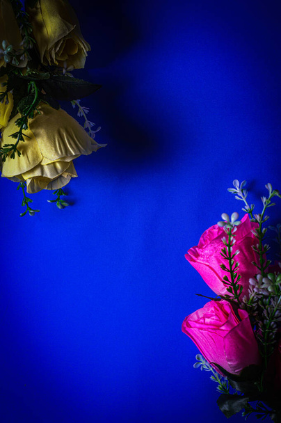 bouquets of artificial pink and yellow flowers on a blue background - Photo, image