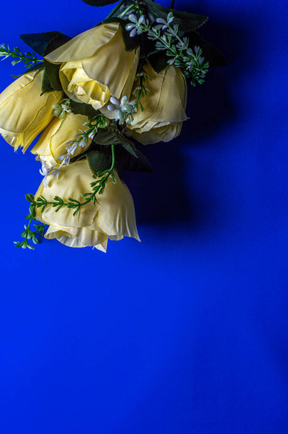 bouquet of yellow artificial flowers on a blue background - Foto, imagen