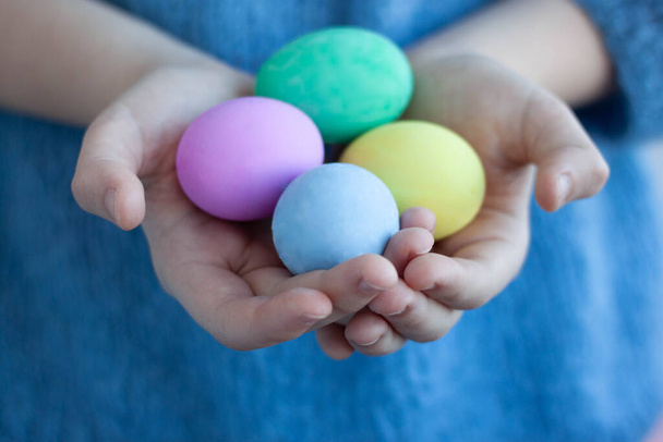 Hands are shaking four eggs painted for the Easter holiday Selective focus - Foto, afbeelding