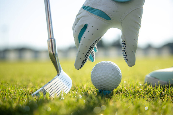 Рука в рукавичці розміщення м'яча для гольфу на трійнику
 - Фото, зображення