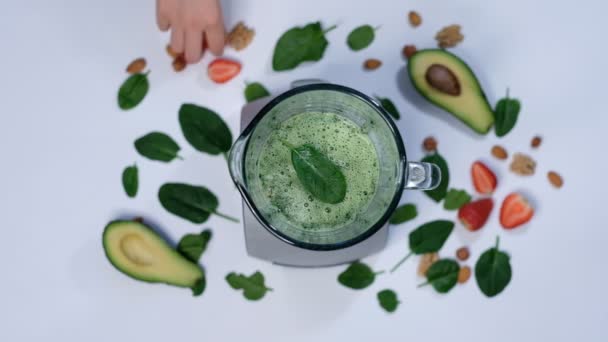 Gezonde groene smoothie gemengd met een blender. spinazie en avocado op een witte achtergrond bovenaanzicht. Sluiten van het koken in slow motion. - Video