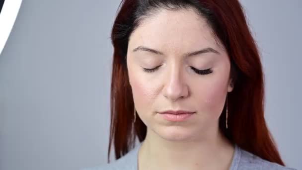 Portrait of a woman on eyelash extension procedure. Before after increasing the volume of eyelashes. The girl opens her eyes with one painted eye. - Imágenes, Vídeo