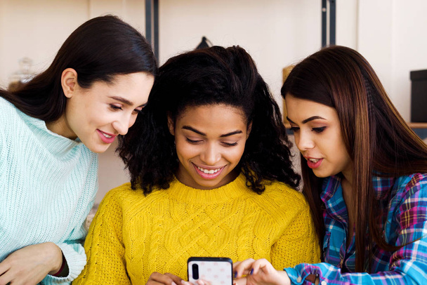 Amiable multiracial girls browsing social media using smartphone at home - Valokuva, kuva