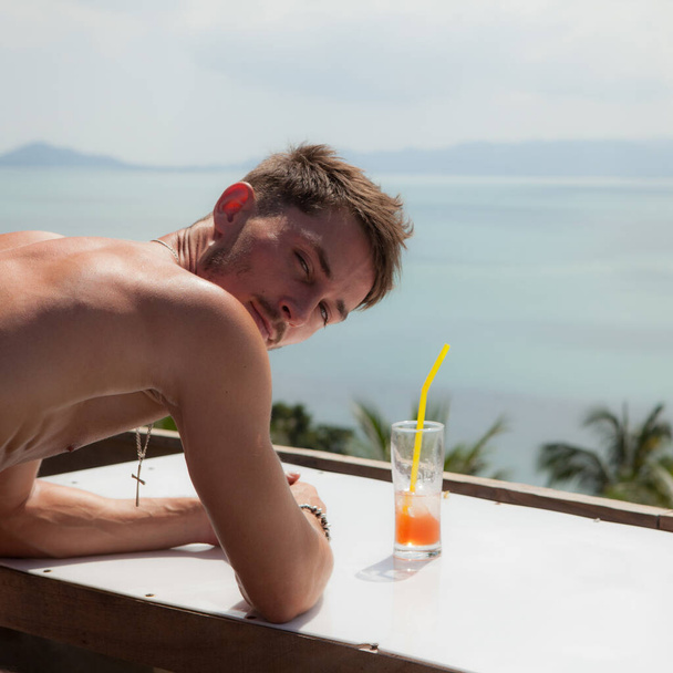 Pihentető vonzó fiatalember trópusi táj ellen. - Fotó, kép