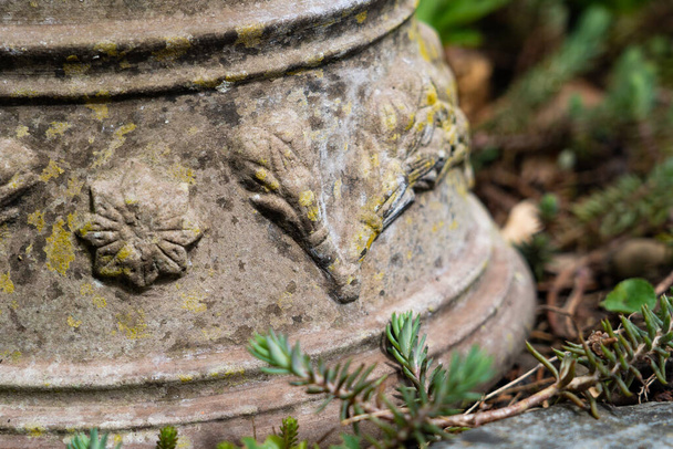 Maceta de cerámica rota inversa con esculturas ornamentales en el suelo del macizo de flores. de cerca
. - Foto, imagen