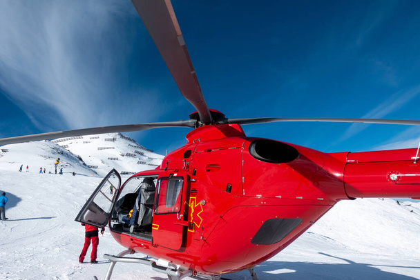 un hélicoptère de sauvetage rouge se tient sur les montagnes enneigées des Alpes autrichiennes
 - Photo, image