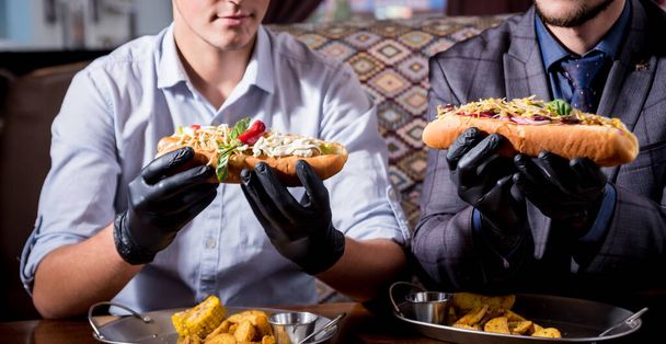 zwei hungrige junge Männer, die im Café einen Hot Dog essen. Restaurant - Foto, Bild