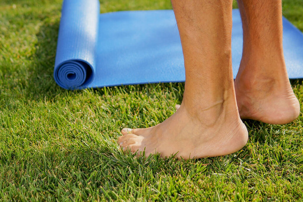Man is going yoga practice outdoors on a sunny meadow. Yoga legs concept - Foto, Bild