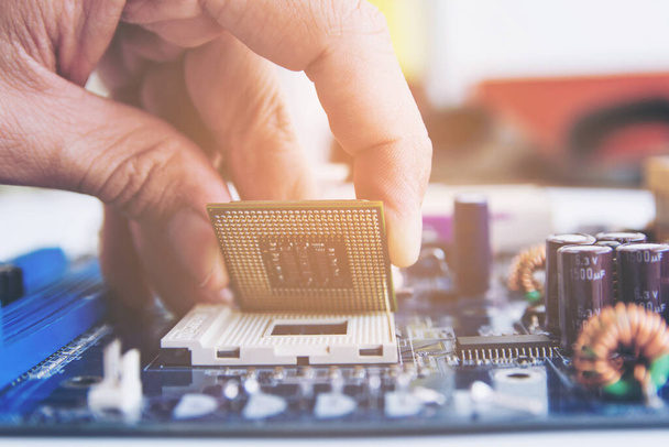 Technician installing CPU chip microprocessor to socket on motherboard  - 写真・画像