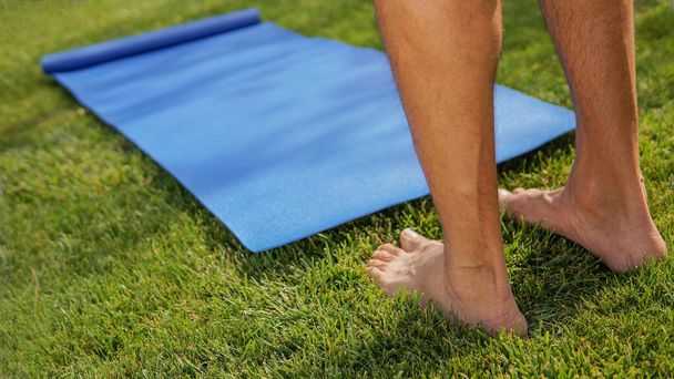 El hombre va a practicar yoga al aire libre en un prado soleado. Concepto piernas de yoga
 - Foto, imagen
