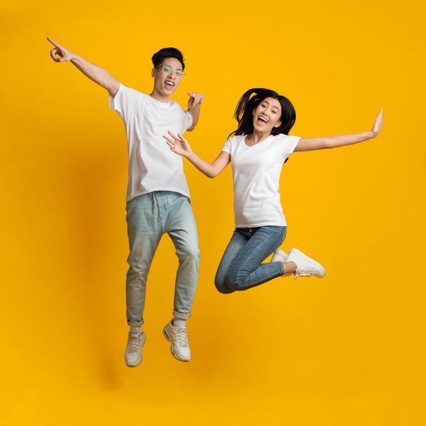 Carefree asian millennial man and woman jumping in air - Foto, afbeelding